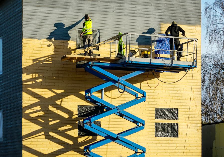 Crew painting a commercial building facade from a scissor lift