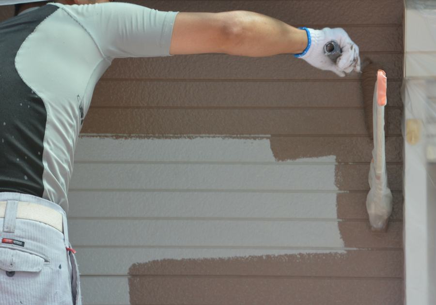 Fresh paint being rolled onto prepared exterior siding