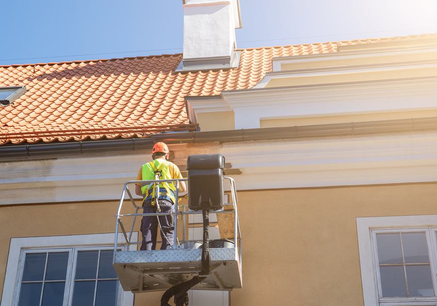 Painter on a lift repainting a two-storey house exterior