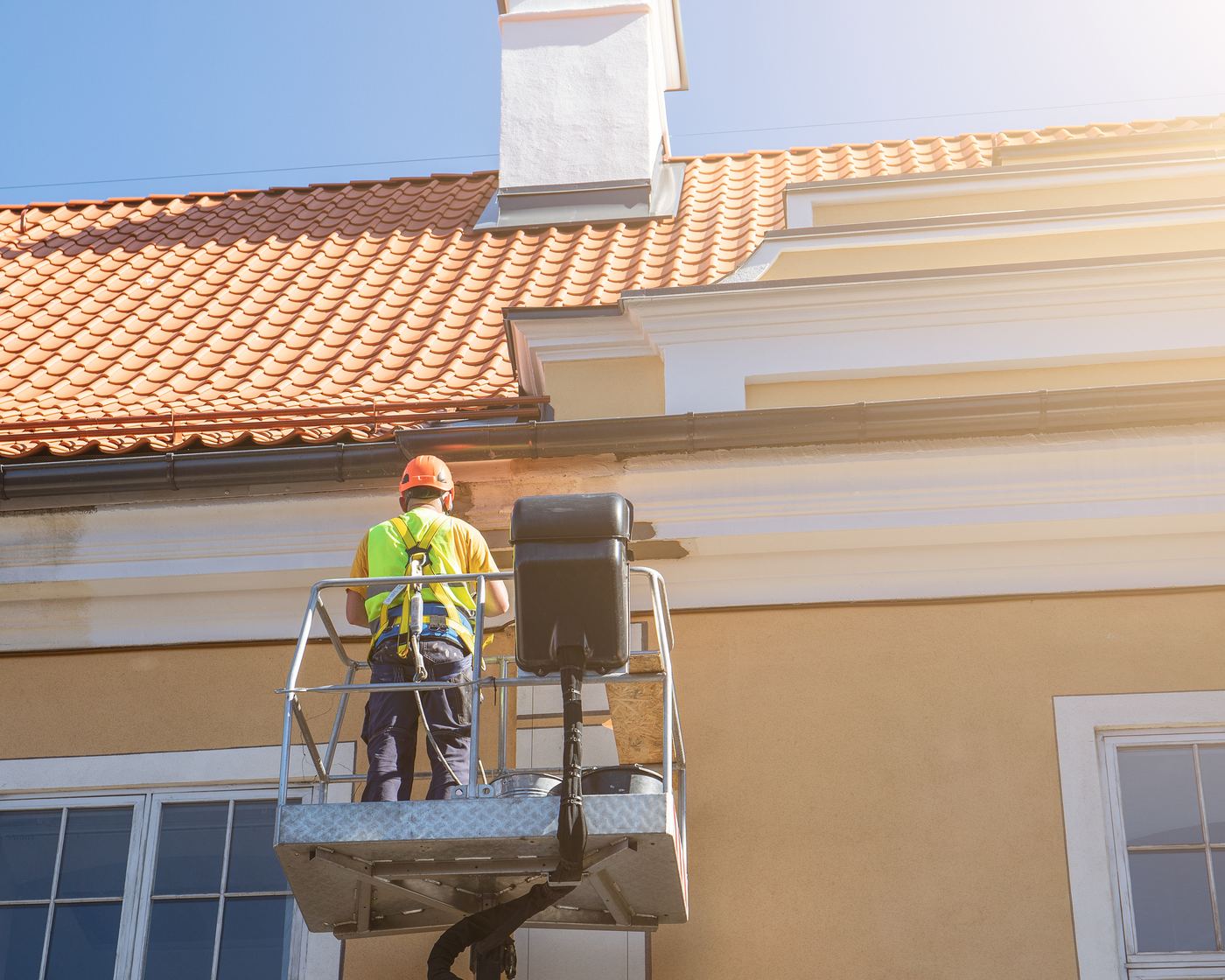 Painter on a lift coating the exterior of a home